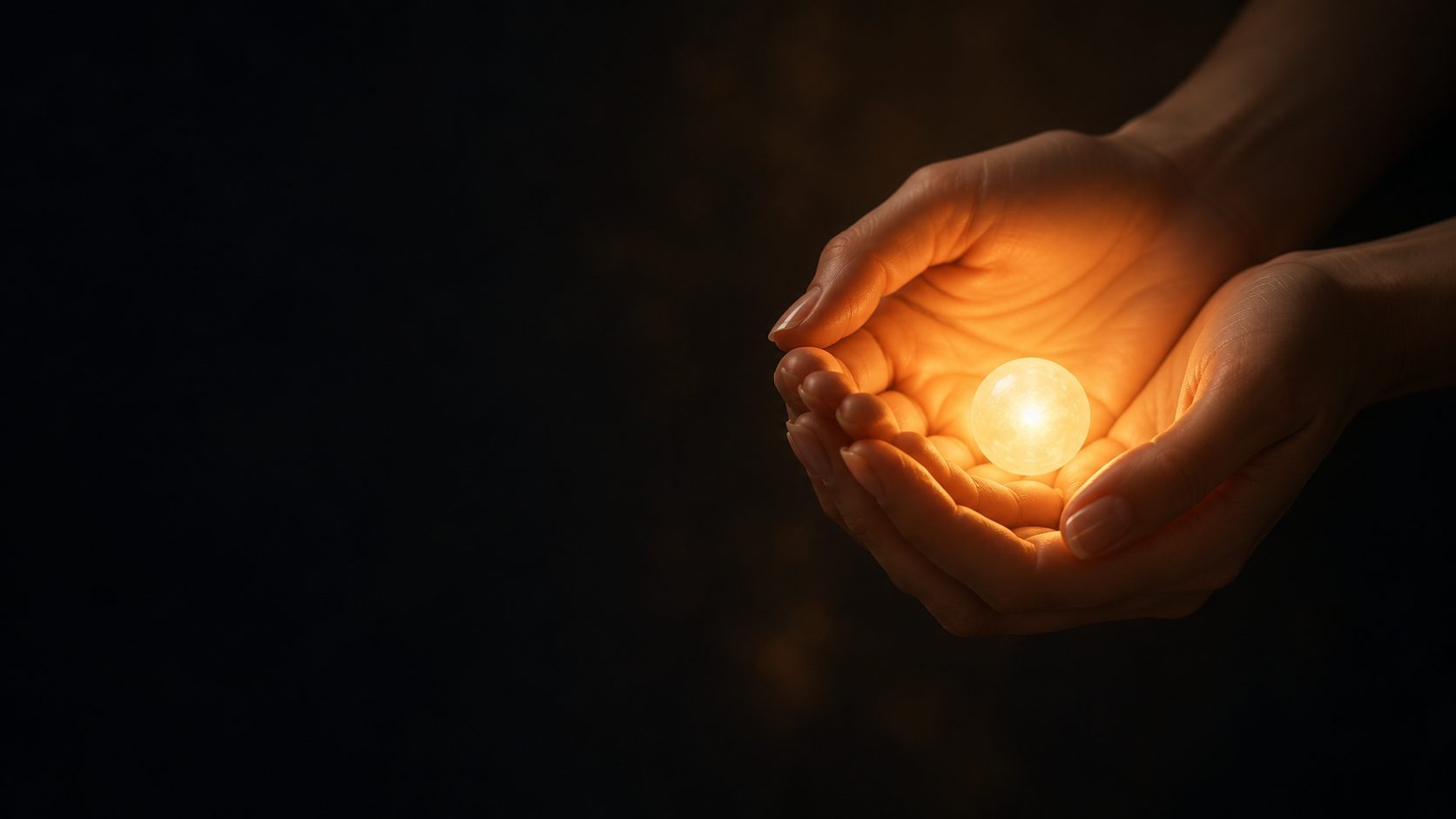 Two hands hold a small warm light in the dark.