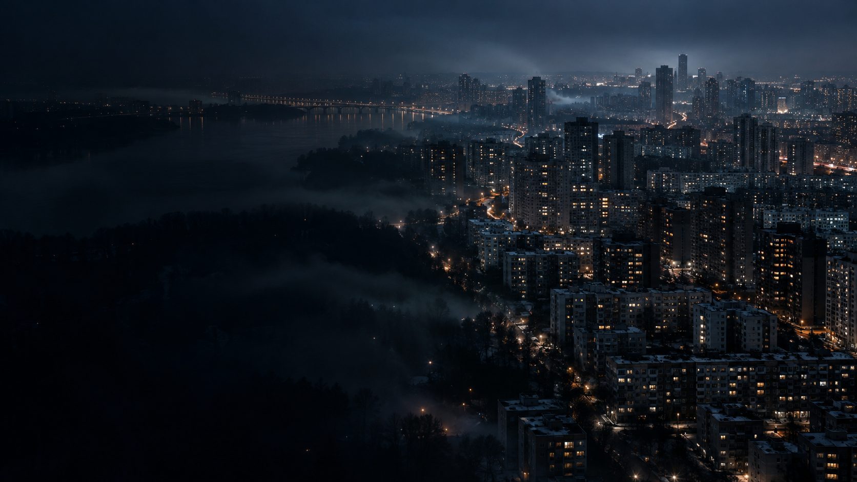 A city at night from above, windows going dark in patches.